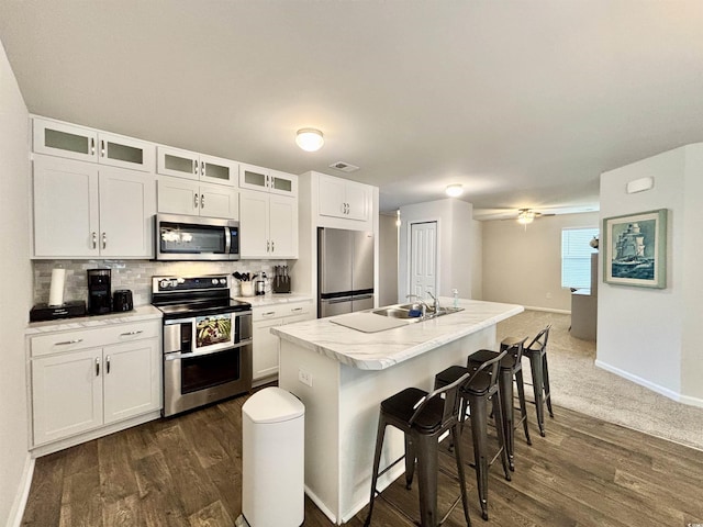 kitchen featuring a breakfast bar, ceiling fan, an island with sink, white cabinetry, and stainless steel appliances