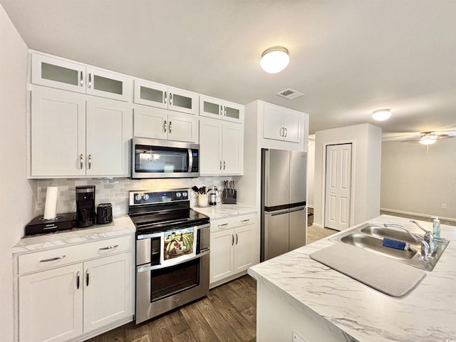 kitchen featuring tasteful backsplash, light stone countertops, white cabinets, and stainless steel appliances