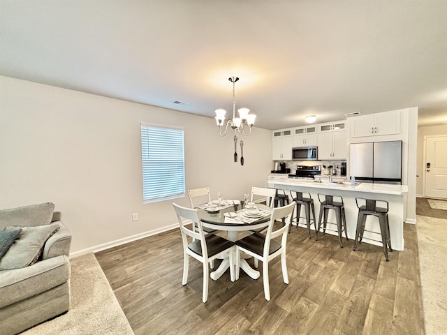 dining space with hardwood / wood-style flooring and an inviting chandelier