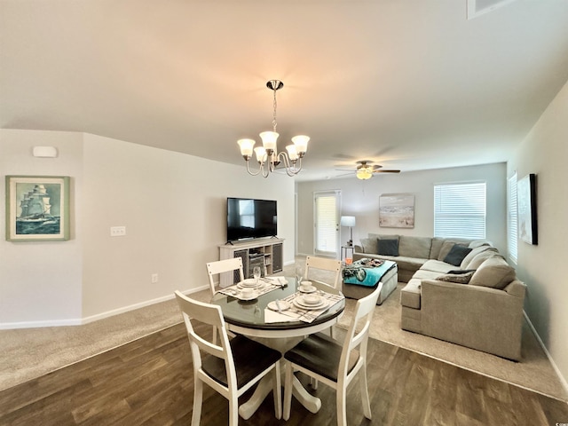 dining space with dark hardwood / wood-style flooring and ceiling fan with notable chandelier