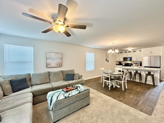 living room with ceiling fan with notable chandelier and dark hardwood / wood-style flooring