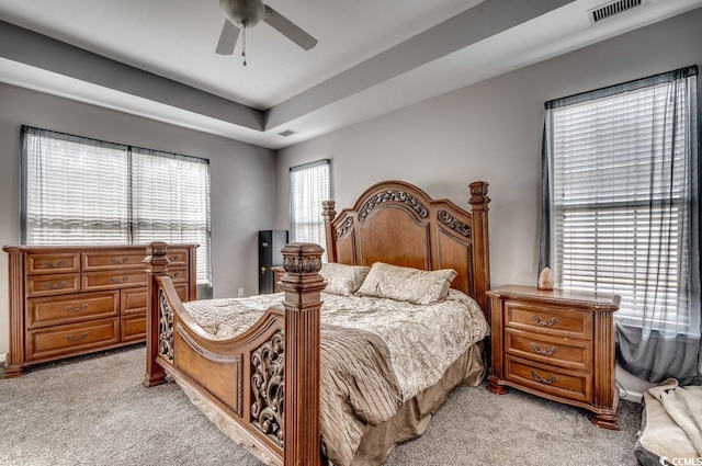 bedroom with ceiling fan, a raised ceiling, and light carpet