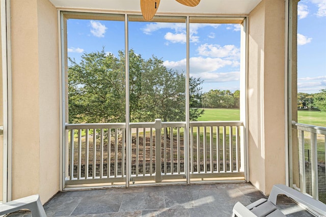 unfurnished sunroom featuring ceiling fan