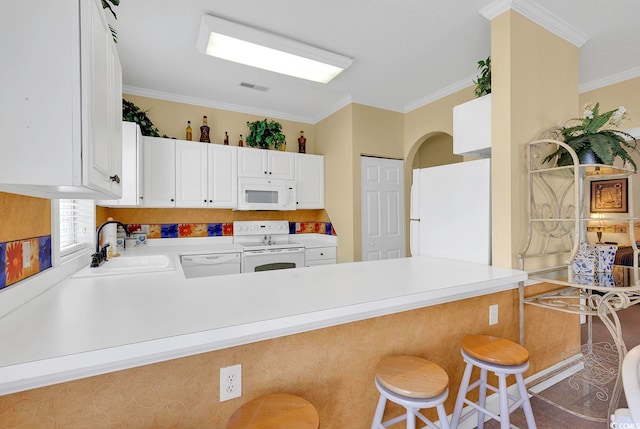 kitchen featuring ornamental molding, kitchen peninsula, a kitchen breakfast bar, and white appliances