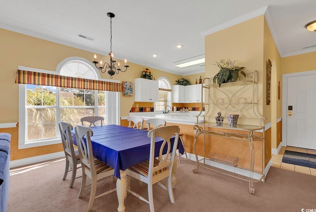 dining space with light colored carpet, a notable chandelier, sink, a textured ceiling, and ornamental molding