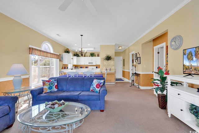 living room with ornamental molding, ceiling fan with notable chandelier, and carpet floors