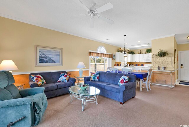 carpeted living room with ornamental molding and ceiling fan with notable chandelier