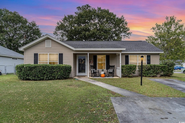 ranch-style home featuring a lawn and covered porch