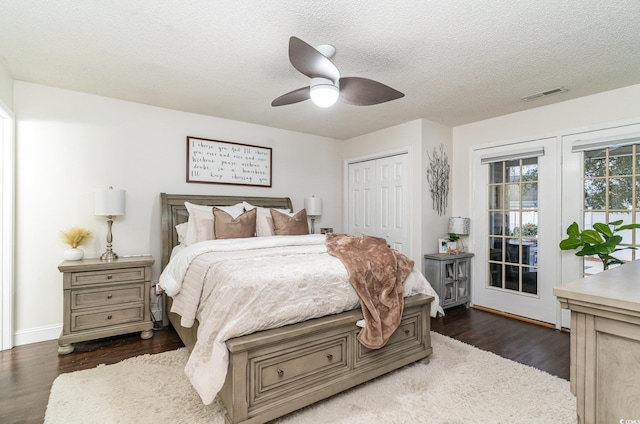 bedroom with a textured ceiling, a closet, dark hardwood / wood-style floors, and ceiling fan