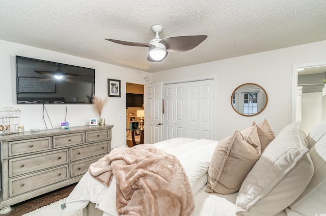 bedroom with a textured ceiling, a closet, dark hardwood / wood-style floors, and ceiling fan