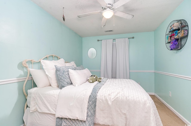 bedroom with ceiling fan, light carpet, and a textured ceiling