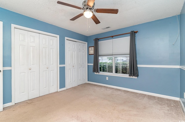 unfurnished bedroom featuring light carpet, ceiling fan, and a textured ceiling