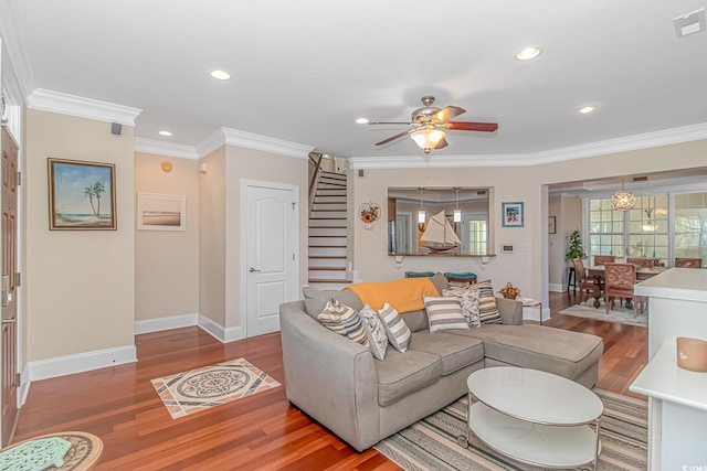 living room featuring wood finished floors, stairs, and ornamental molding