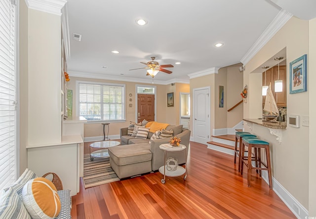 living room featuring light wood-style flooring, crown molding, ceiling fan, and visible vents