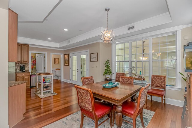 dining room featuring french doors, hardwood / wood-style floors, ornamental molding, and a raised ceiling