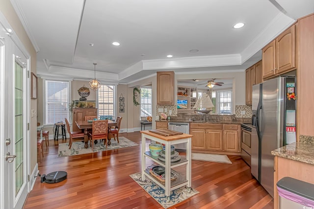 kitchen featuring decorative backsplash, light wood-style flooring, stainless steel appliances, and a tray ceiling