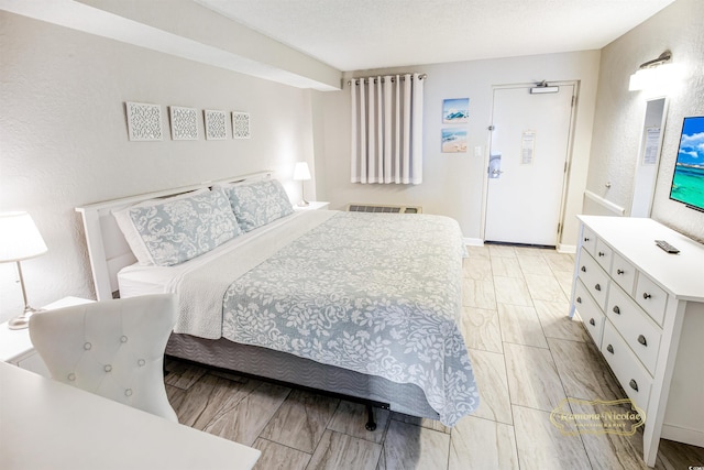 bedroom featuring a textured ceiling and light hardwood / wood-style flooring