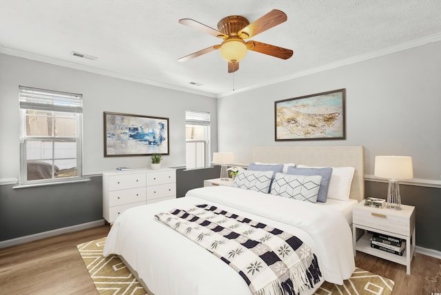 bedroom featuring a textured ceiling, hardwood / wood-style flooring, ceiling fan, and ornamental molding