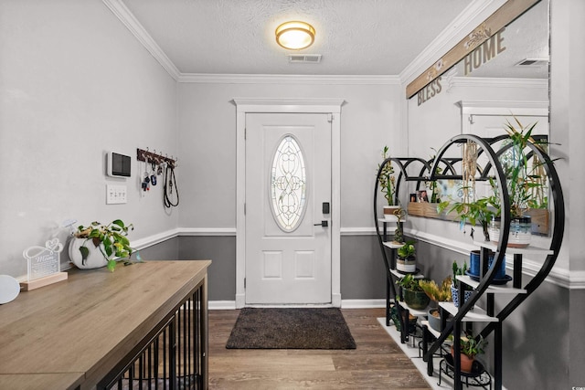 entryway with hardwood / wood-style floors, a textured ceiling, and crown molding