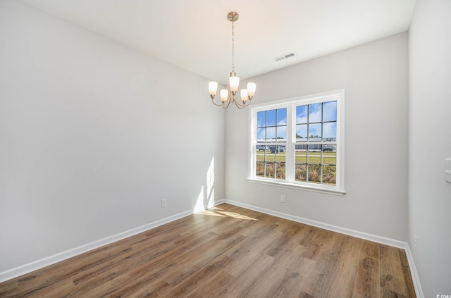 empty room with an inviting chandelier and wood-type flooring