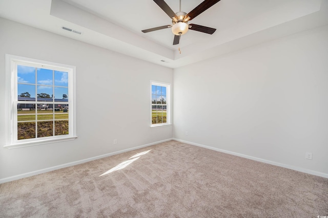 carpeted spare room with ceiling fan and a raised ceiling