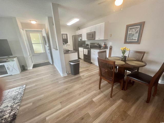 dining room with ceiling fan, sink, a textured ceiling, and light wood-type flooring