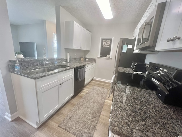 kitchen with sink, black appliances, light hardwood / wood-style floors, and white cabinets