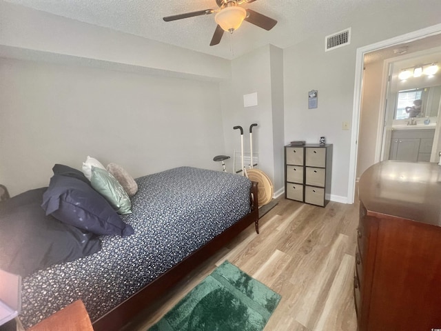 bedroom featuring ceiling fan, sink, a textured ceiling, and light wood-type flooring