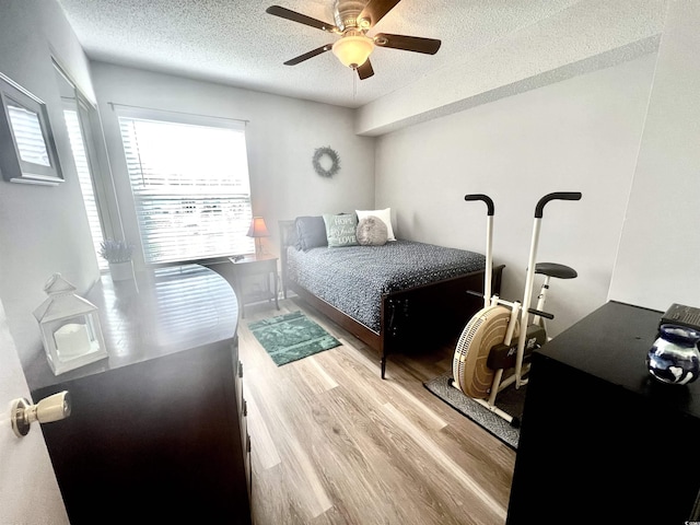 bedroom with wood finished floors, a textured ceiling, and ceiling fan