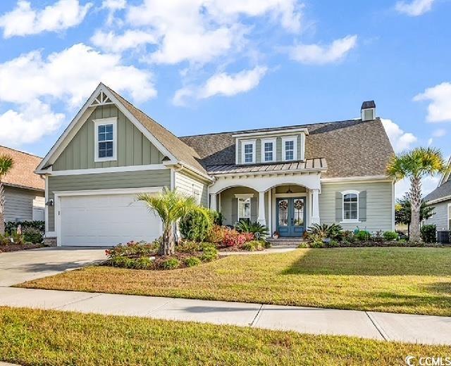 view of front of house featuring a garage, a front lawn, and french doors