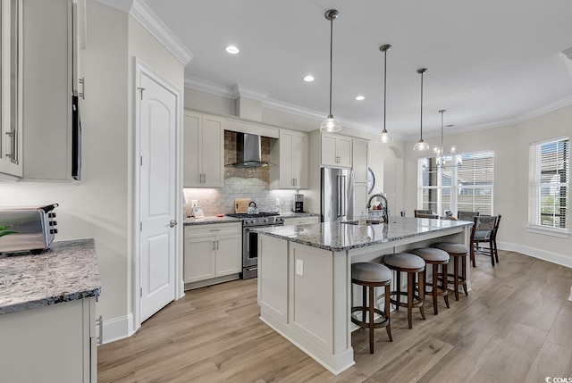 kitchen featuring stainless steel appliances, white cabinetry, a kitchen island with sink, and wall chimney exhaust hood