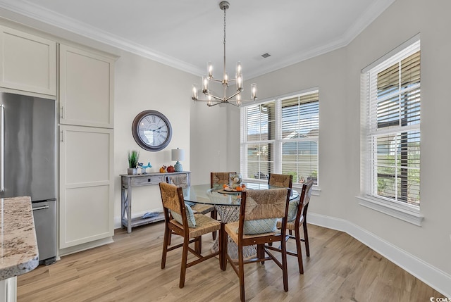 dining area with light hardwood / wood-style floors, a wealth of natural light, crown molding, and a notable chandelier