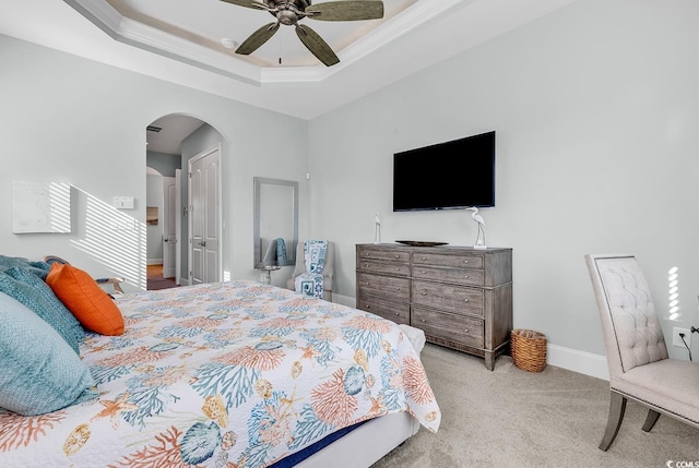 carpeted bedroom with ceiling fan, ornamental molding, and a raised ceiling