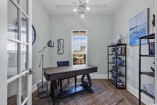 office space featuring ornamental molding, a chandelier, a raised ceiling, and dark hardwood / wood-style flooring