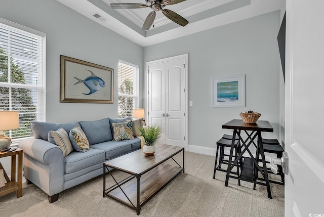 carpeted living room with ceiling fan, crown molding, and a tray ceiling