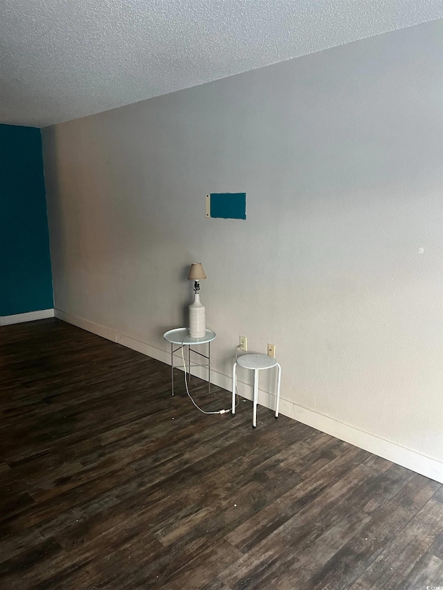 unfurnished room featuring dark hardwood / wood-style flooring and a textured ceiling