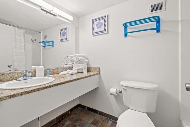 1501 Ocean Blvd S Unit 422, Myrtle Beach, SC 29577 - full bath featuring toilet, baseboards, vanity, curtained shower, and stone finish floors