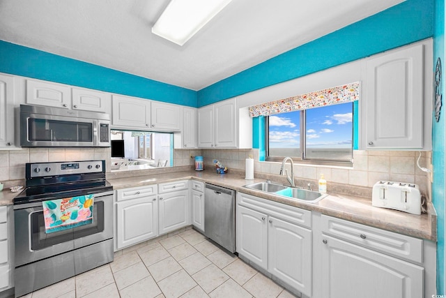 kitchen with white cabinets, stainless steel appliances, a wealth of natural light, and sink