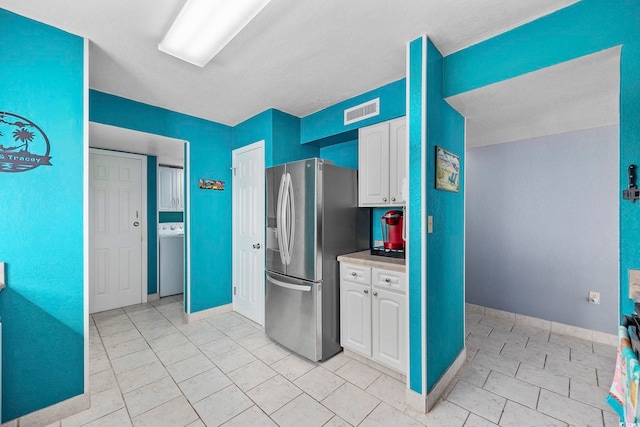 kitchen with stainless steel fridge and white cabinetry