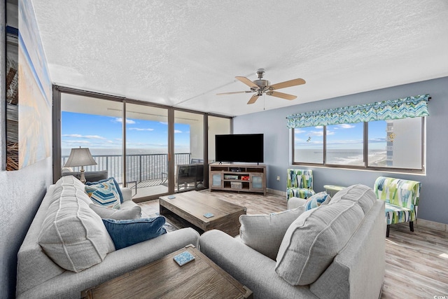 living room featuring a textured ceiling, light wood-type flooring, and ceiling fan