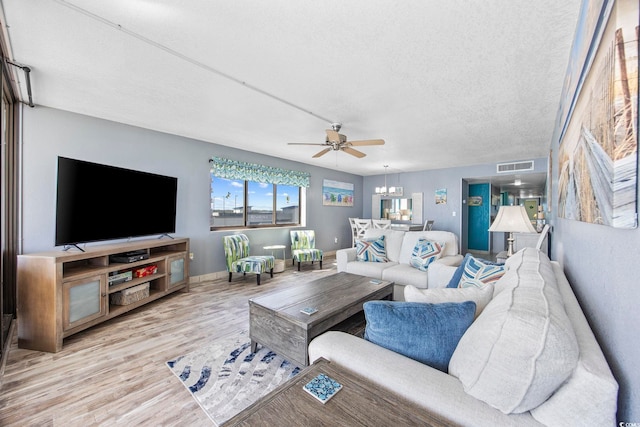 living room featuring ceiling fan, a textured ceiling, and light wood-type flooring