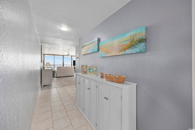 hall featuring a textured ceiling and light tile patterned flooring