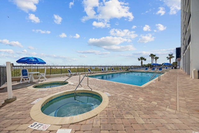 view of swimming pool featuring a hot tub and a patio area