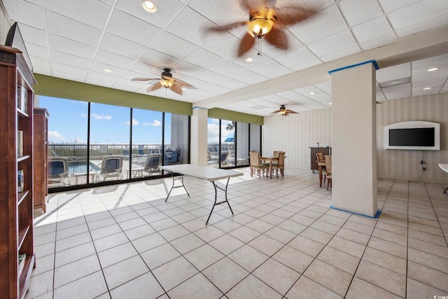 playroom featuring light tile patterned floors, a water view, a drop ceiling, and ceiling fan