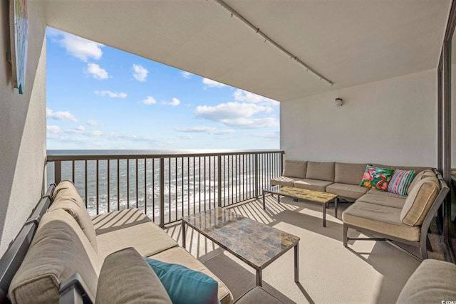 balcony with an outdoor living space and a water view