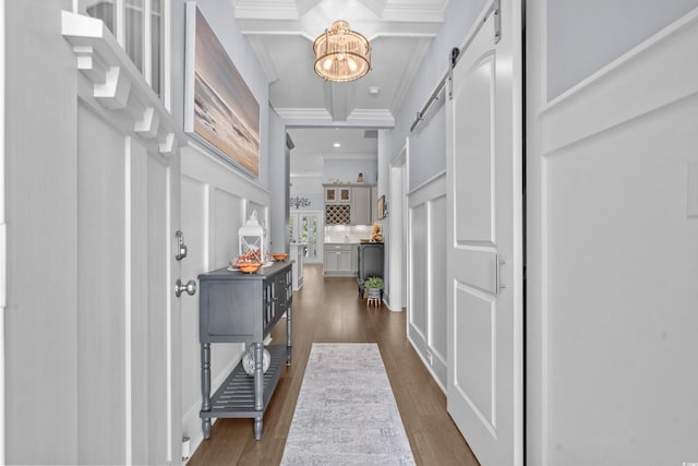 foyer featuring a barn door, beam ceiling, dark wood-type flooring, and ornamental molding