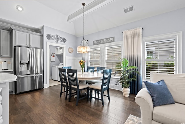 dining room featuring dark wood-type flooring, lofted ceiling with beams, a notable chandelier, and separate washer and dryer