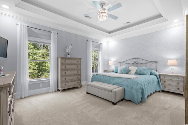 bedroom with light colored carpet, ceiling fan, crown molding, and a tray ceiling