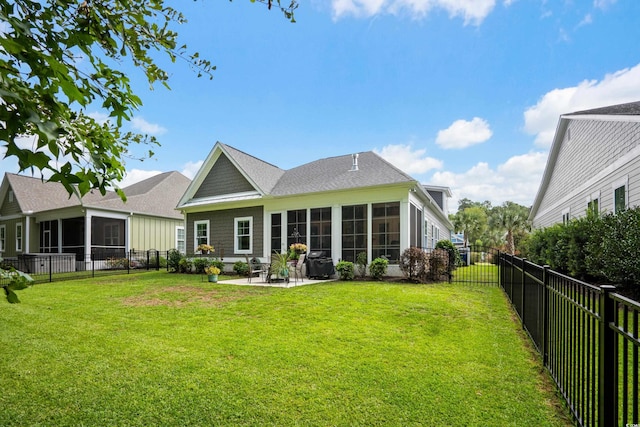 rear view of house featuring a lawn, a patio, and a sunroom