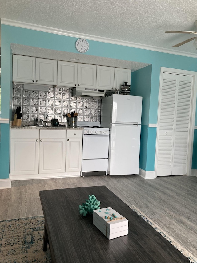 kitchen with tasteful backsplash, white appliances, dark wood-type flooring, sink, and white cabinetry